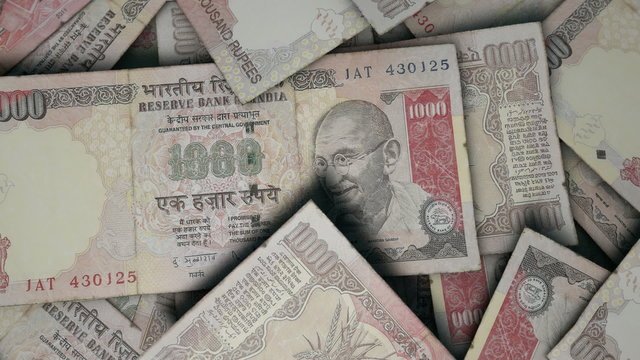 An extreme close up pan of a pile of randomly scattered indian rupee banknotes