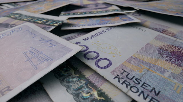 An extreme close up pan of a pile of randomly scattered norwegian kroner banknotes