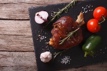 Baked pork shank and vegetables on a slate board. horizontal top view
