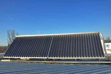 Energy efficiency concept. Closeup of vacuum solar water heating system on the house metal roof. © bildlove