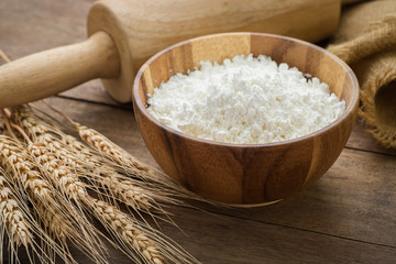 Fototapeta na wymiar Flour in bowl and wheat on wooden table