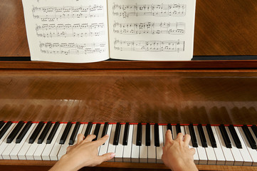 Woman's hands on the keyboard of the piano closeup