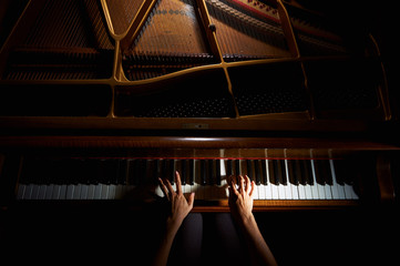 Naklejka premium Ręce kobiety na klawiaturze fortepianu w nocy zbliżenie
