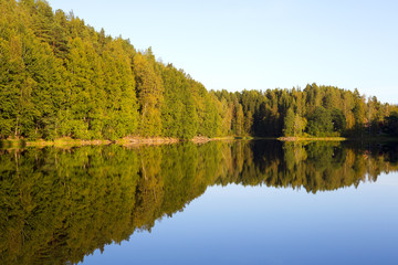 Amazing sunset scenery from Finland. The colorful forest makes a beautiful reflections on the still water surface