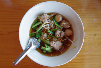 Bowl of noodles with pork on the wooden table