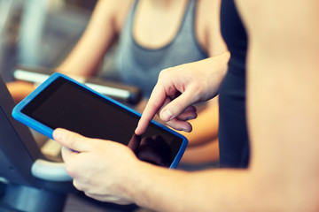 close up of trainer hands with tablet pc in gym