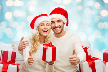 happy couple with christmas gifts and thumbs up