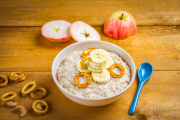 Oatmeal porridge in bowl with bananas, healthy breakfast for kid