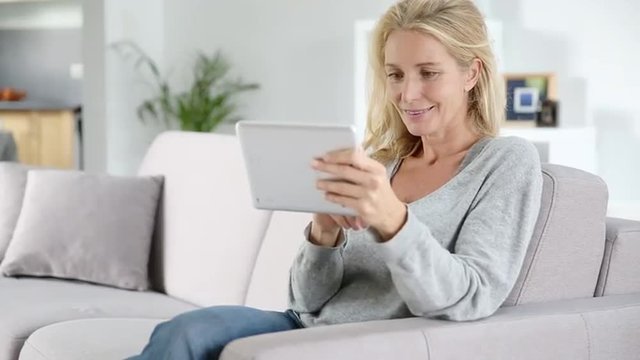 Mature woman, using a mobil phone at home