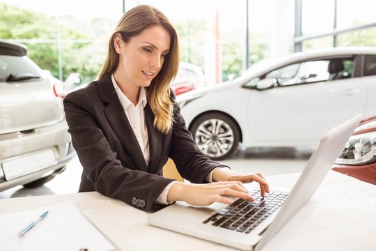Smiling saleswoman typing on her laptop