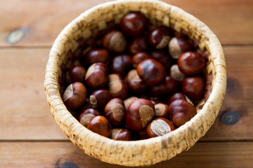 close up of chestnuts in basket on wooden table