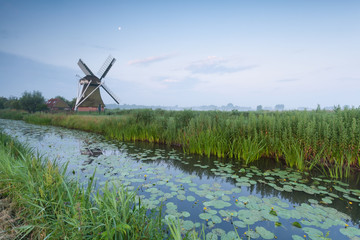 Dutch windmill bu river and moon