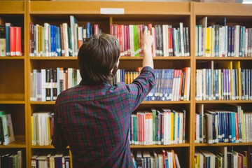 Student picking a book from shelf in library