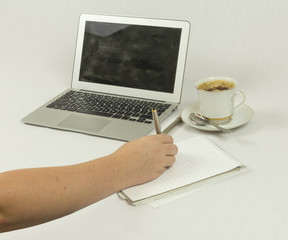 Young Girl Holding a Silver Pen with Paper Notebook Laptop Computer and a Cup of Coffee against White in Studio