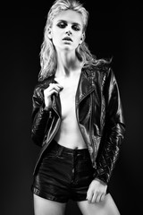 Daring girl model in black leather dress, style of rock on naked body, dark makeup and wet hair.  Black-and-white image.