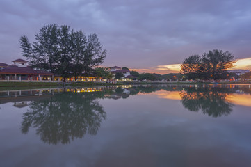 Obraz premium Beautiful sunrise at the lake with blue sky, red and orange clouds, green trees and water with reflection (Malaysia)