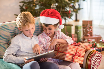 Christmas morning, Two kids sitting having fun with a digital tablet