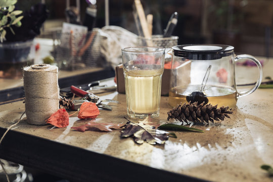 Hot beverage, tea pot, leafs and pinecones on a table