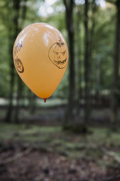 Orange halloween ballon floating in the forest