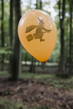 Orange halloween ballon with a witch illustration in the forest