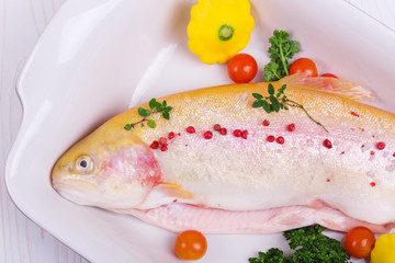 golden trout gutted fish with herbs, cherry tomatoes, squash, herbs in a dish for baking. view from above, from the side, the free space for the inscription.