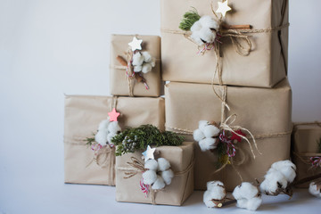 Christmas gift boxes with flowers and decorative objects Eco cotton, cinnamon, spruce branches and jute rope hank over white background,holiday,xmas,christmas  