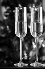 two champagner glasses on glass table with bokeh background in black and white
