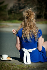 beautiful girl sits in the sun with coffee & cigarette