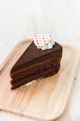 Chocolate cake slice on wooden plate.