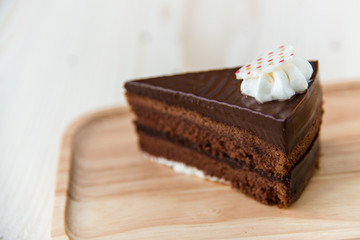 Chocolate cake slice on wooden plate.