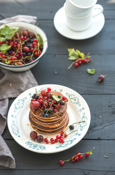 Breakfast set. Buckwheat pancakes with fresh berries and honey on rustic plate over black wooden table