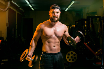Fototapeta na wymiar man in gym training with dumbbells