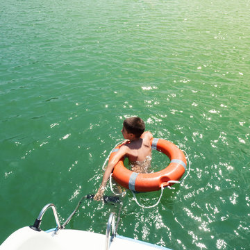 Young Kid Swimming In Lavarone Lake With Life Buoy. Trentino, Italy.