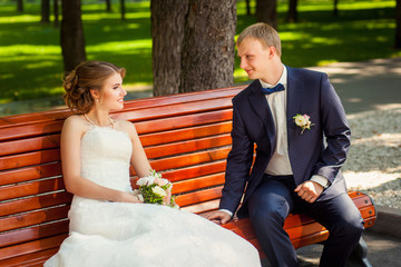 Wedding couple on bench in summer park