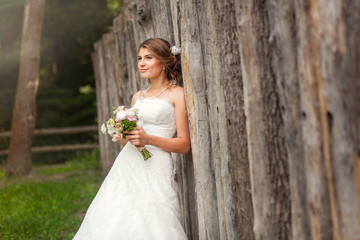 Fototapeta na wymiar Bride in dress near wooden fence