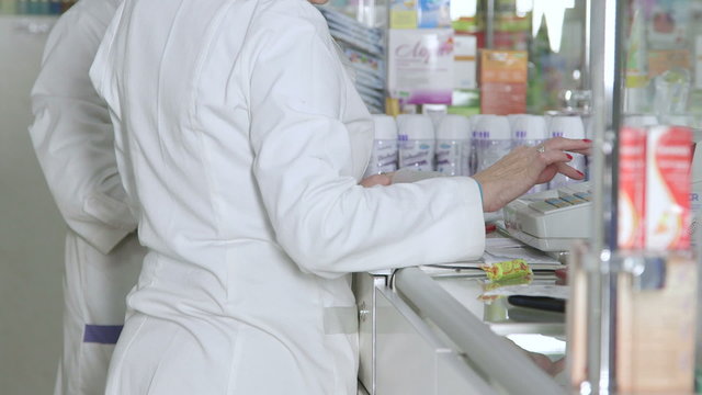 Female pharmacists working at pharmacy shop checkout counter selling medicines to customers