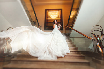 Bride in white wedding dress posing at stairs