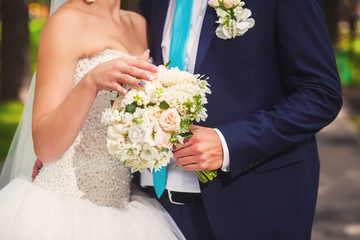 Bride and groom with bouquet in the park