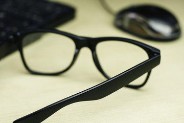 closeup of glasses , keyboard and mouse on table