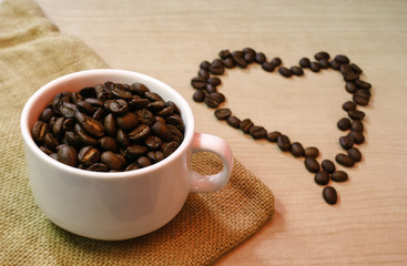 cup of coffee beans with heart coffee beans on the table