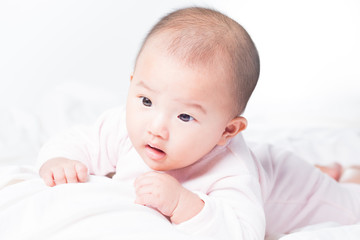 Adorable Asian baby 4-5 months old on white bed & background. Portrait studio light isolated.