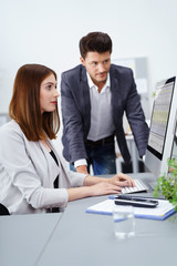 chef und mitarbeiterin schauen gemeinsam auf die zahlen am computer