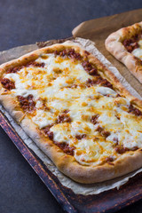 Pizza with meat in a tray, on a kitchen board