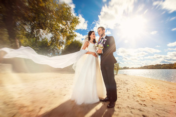 Fototapeta na wymiar Happy bride and groom at wedding on the beach near the river