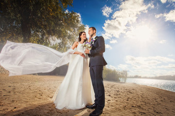 Happy bride and groom at wedding on the beach near the river
