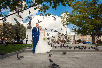 Bride and groom in park with pigeons
