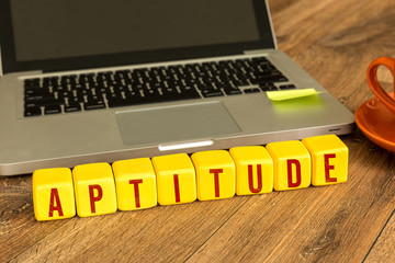Aptitude written on a wooden cube in front of a laptop