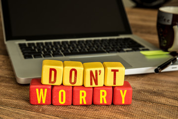 Don't Worry written on a wooden cube in front of a laptop