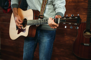 Fototapeta na wymiar man playing guitar. Guitars on wall on background, love music concept