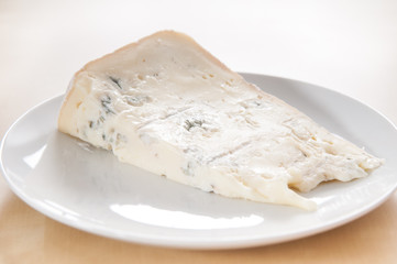 Big slice of fresh Gorgonzola cheese on white ceramic dish - 94737471
